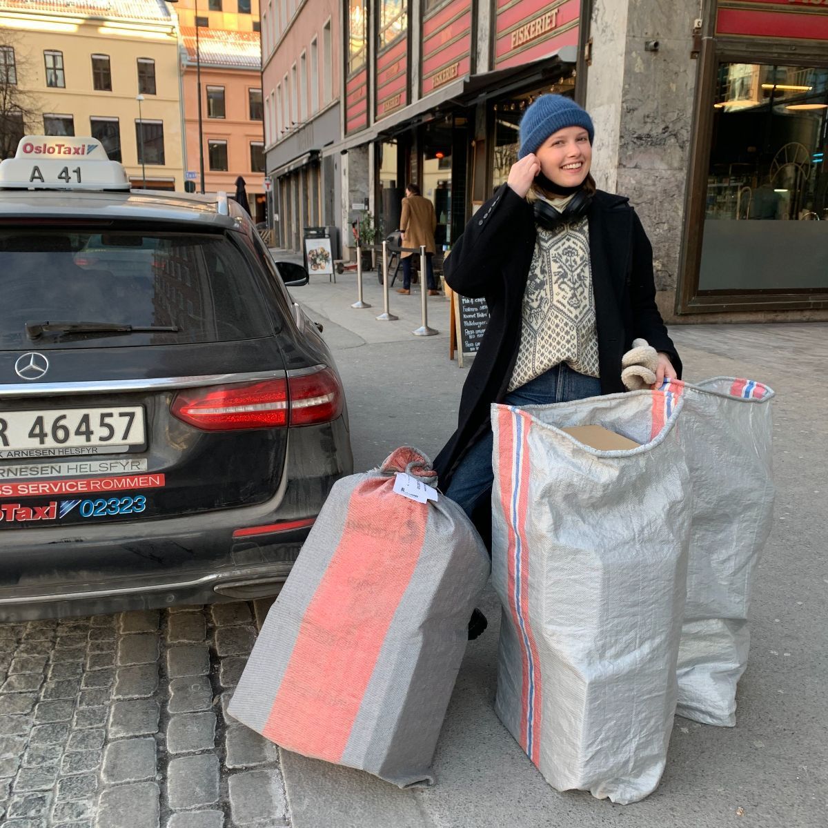 Photo of Camila who has picked up three full bags of returns in a taxi.