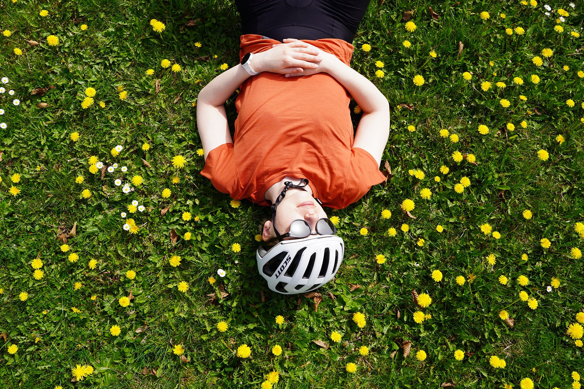 Woman laying flat out on a field of flowers wearing a t-shirt in wool and silk