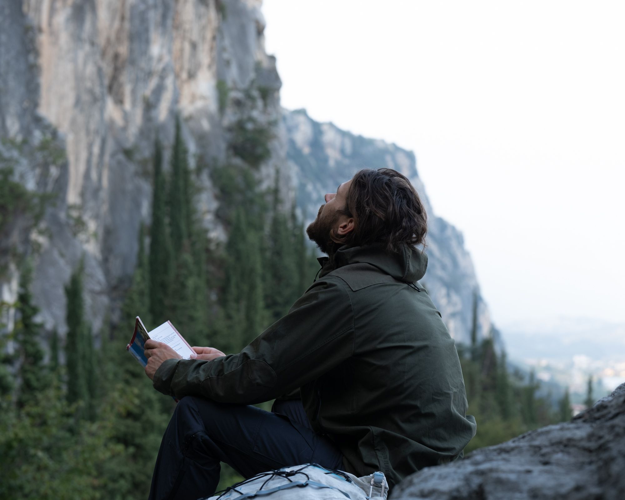 Man spotting routes before climbing. Wearing The Last jacket in green and the last pants in grey