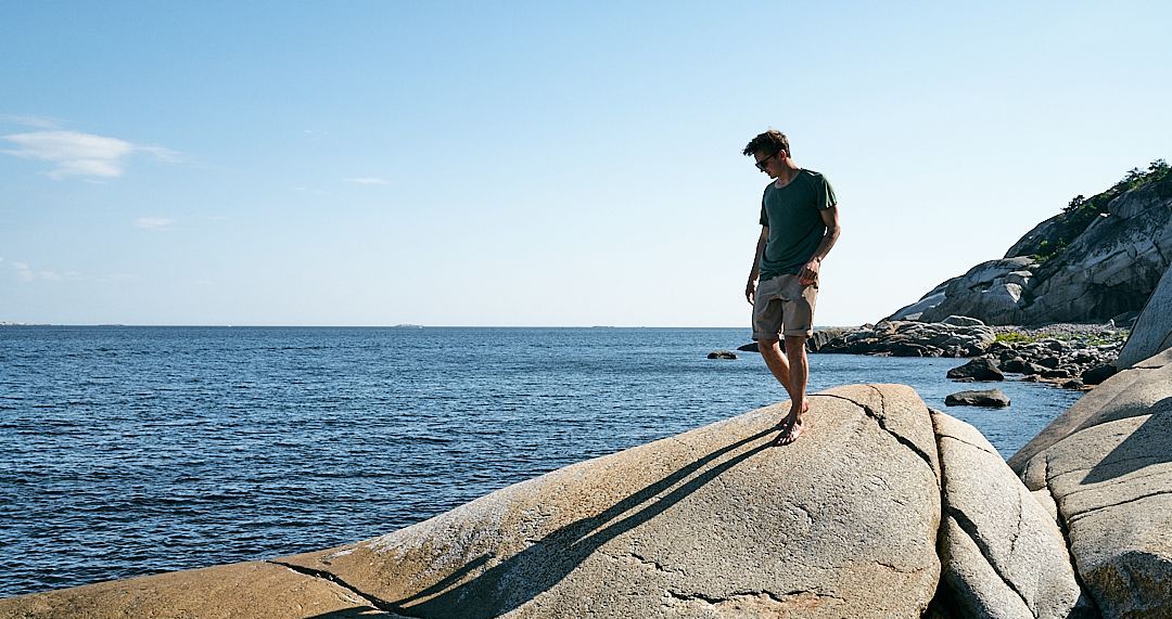 Man in a green t-shirt on a rocky shore.