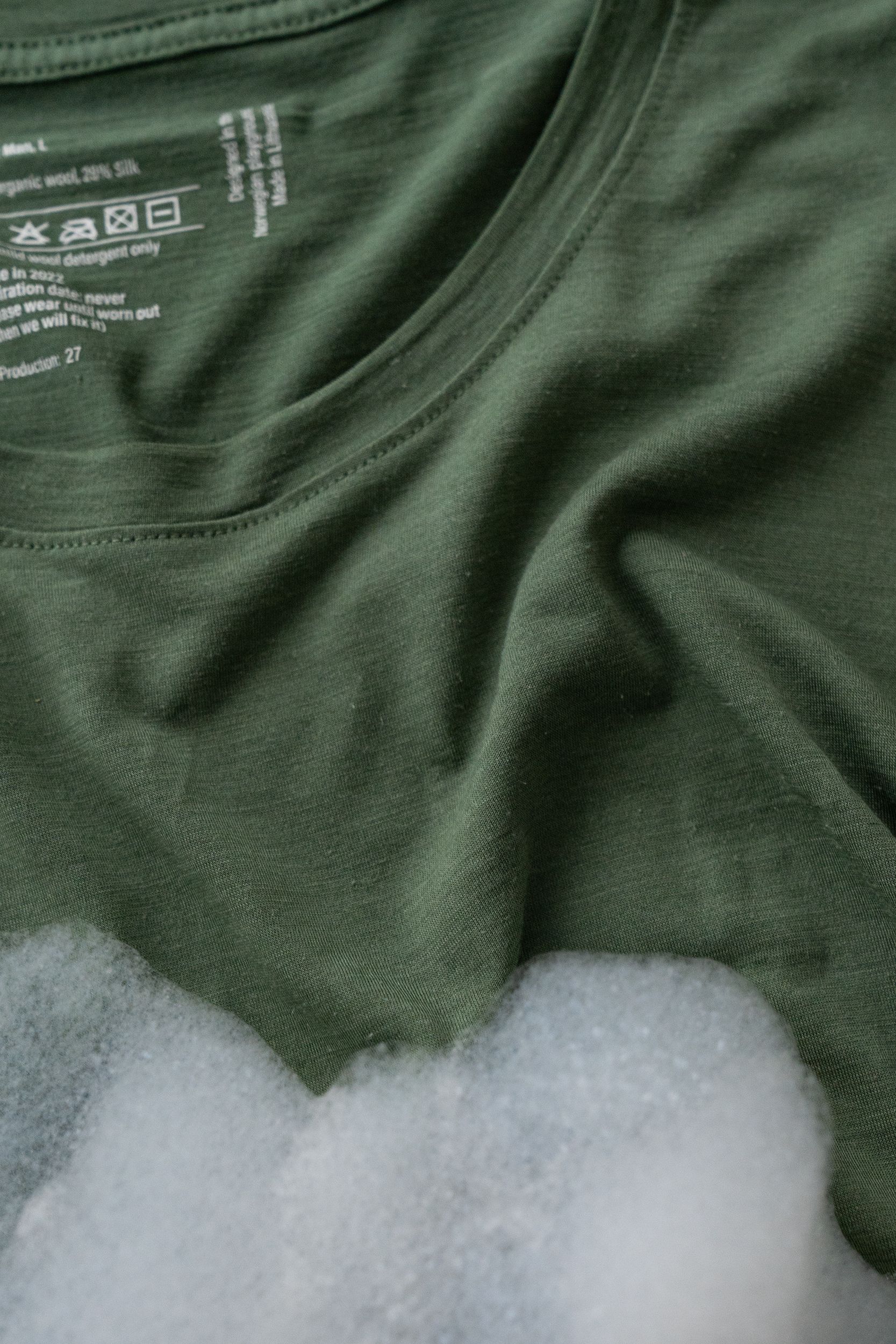 Green sweater with foam to illustrate washing