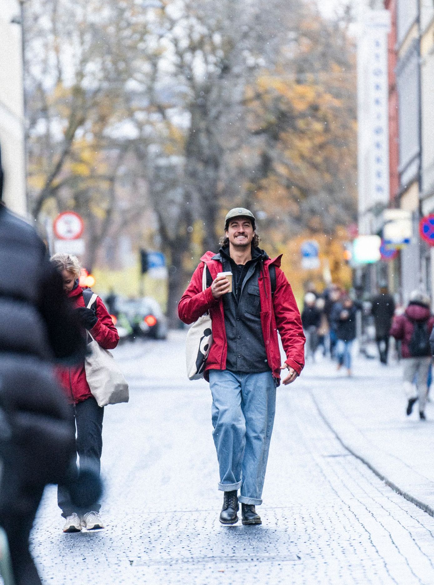 Man in a red The Last Jacket, walking down a street.