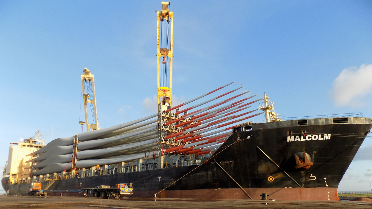 Cargo ship loaded with wind turbine blades at port.