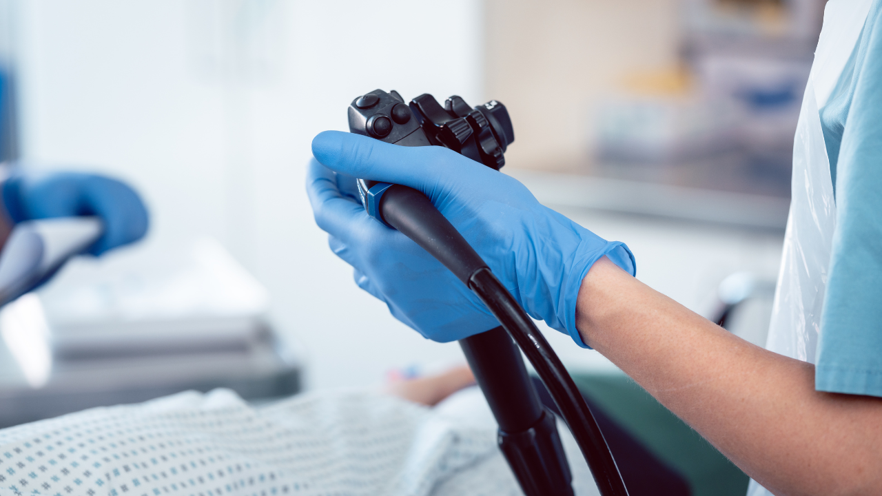 Gloved hands operating a medical endoscope during a procedure.