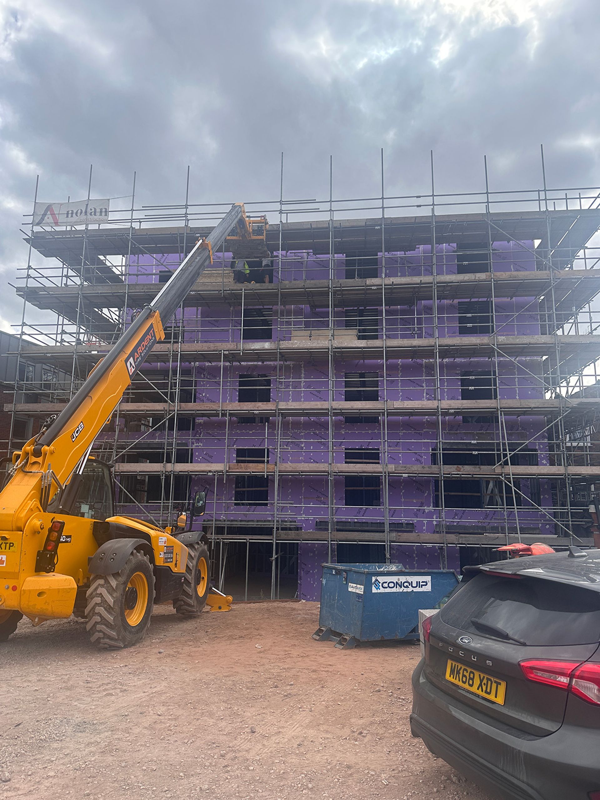 A telehandler raising materials to the top scaffold lift.