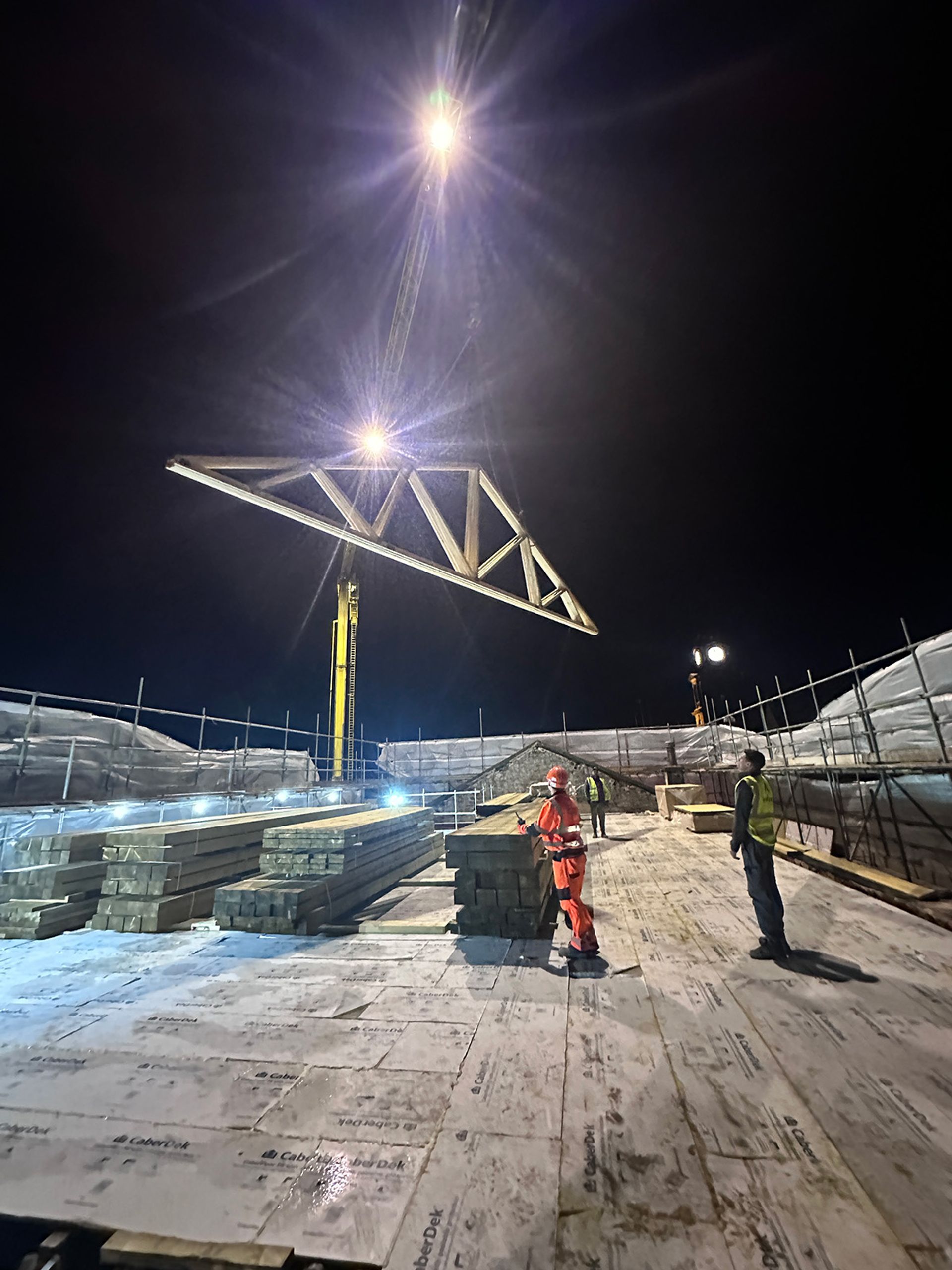 Steel beams being craned into place at night.
