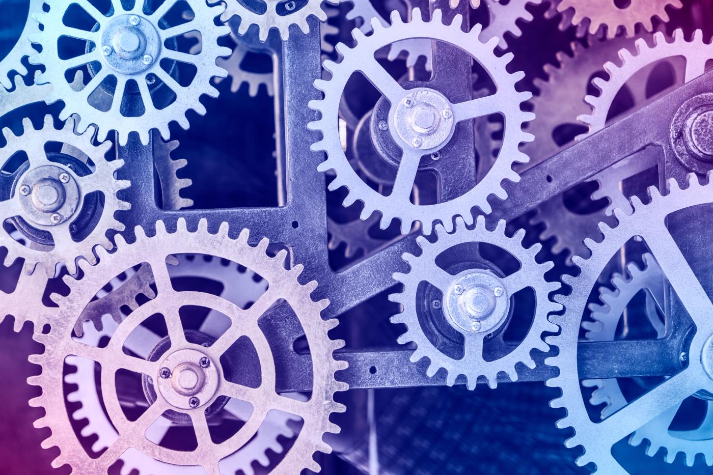Interlocking metal gears meshed together, representing the Growth Engine's three components working as one machine