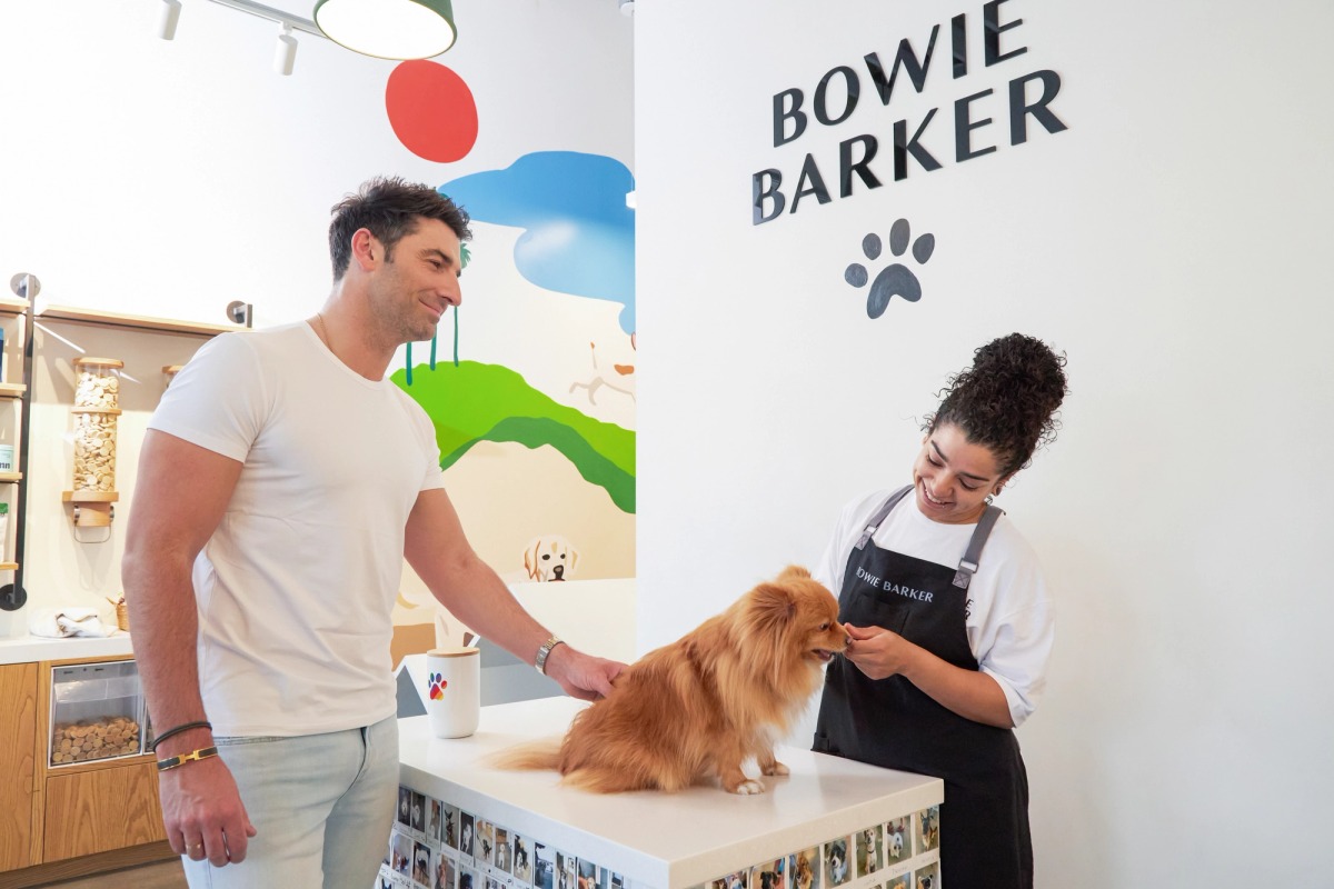 Image of a customer happy at Bowie Barker as a groomer takes care of their dog