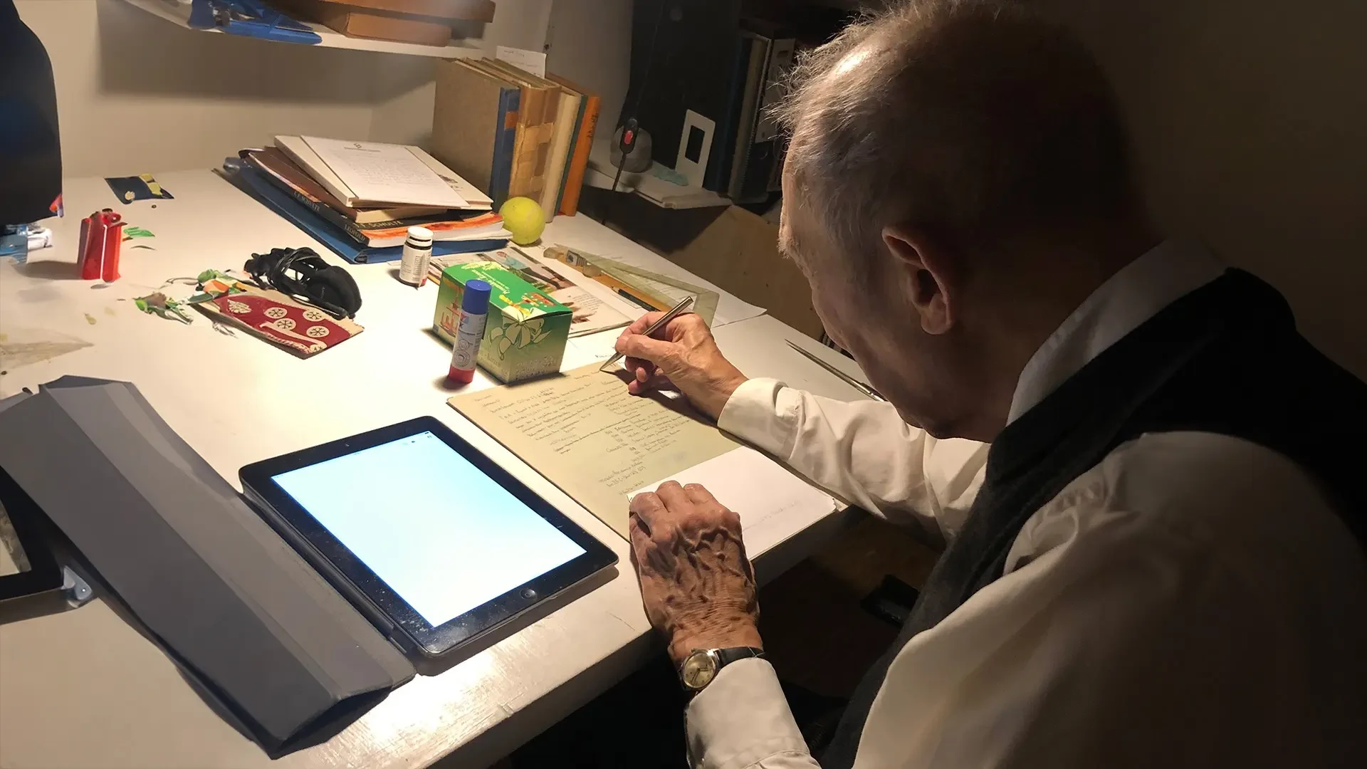 Senior user taking notes while using a tablet during testing