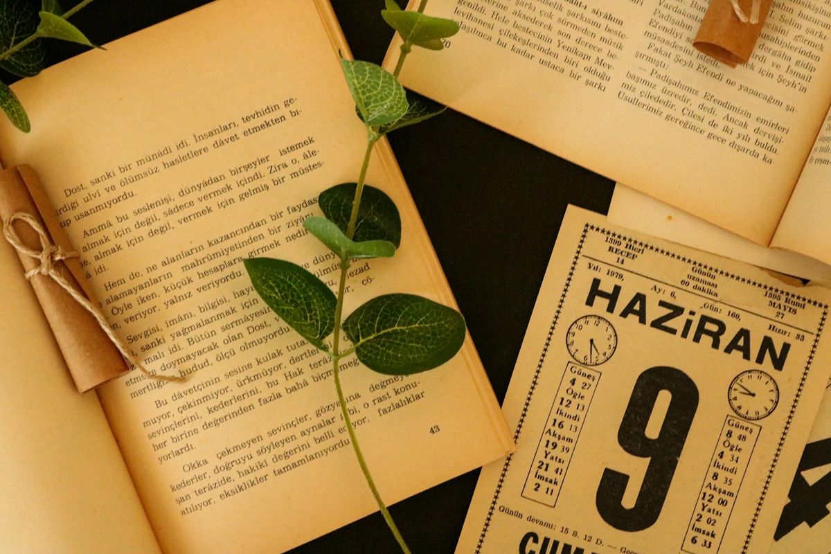 Buku terbuka dengan daun kering dan kalender antik — melambangkan catatan waktu dan rekam jejak historis pengundian HK