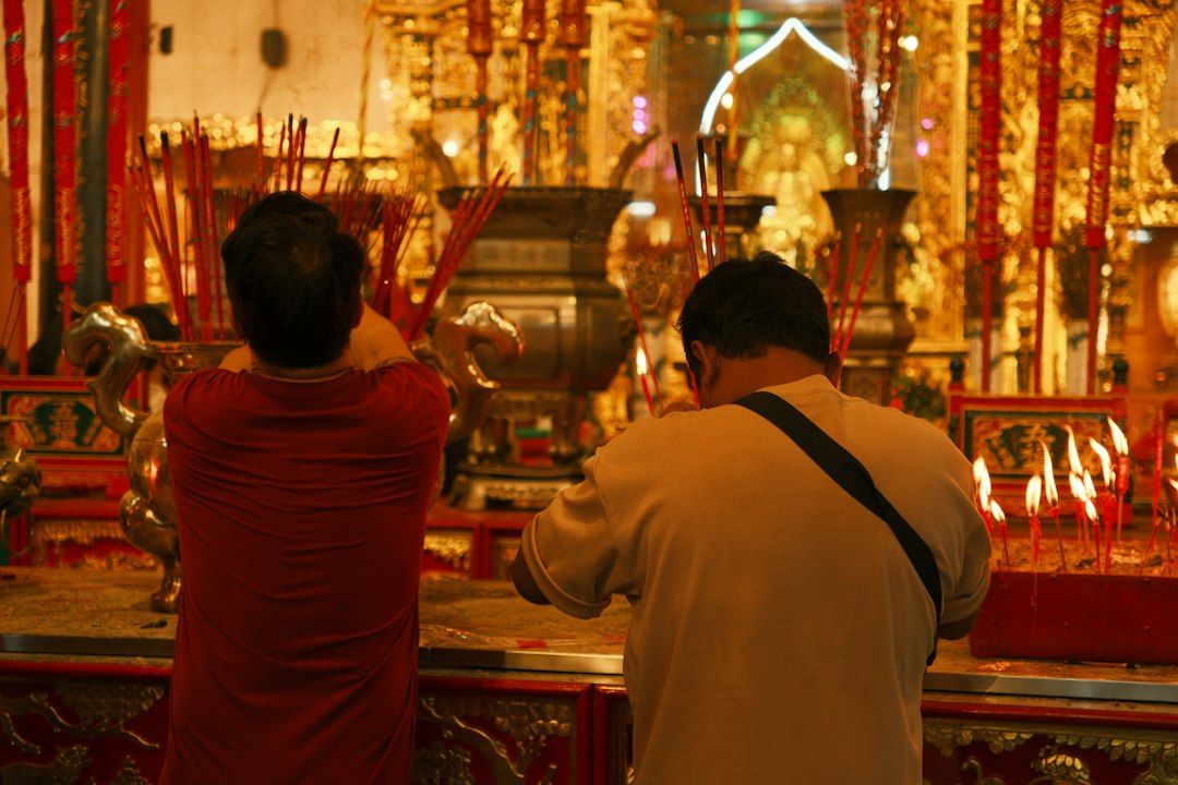 Dua orang berdoa di altar klenteng dengan dupa, tradisi yang melahirkan kepercayaan kode alam