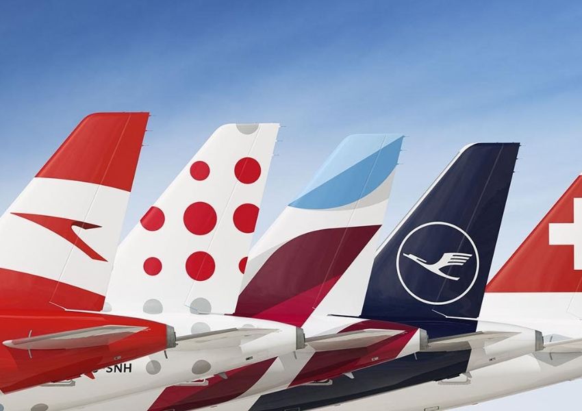 Close-up of five airplane tail fins with various airline liveries against a blue sky.