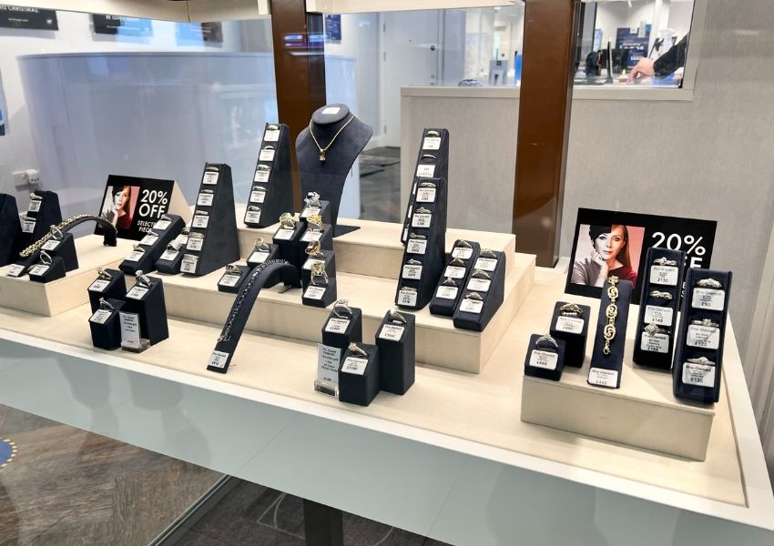 Jewelry display case with rings, necklaces, and bracelets on black velvet stands, and a "20% OFF" sign.