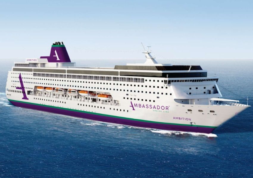 White cruise ship with purple and green accents, named Ambassador Ambition, sails on blue water.