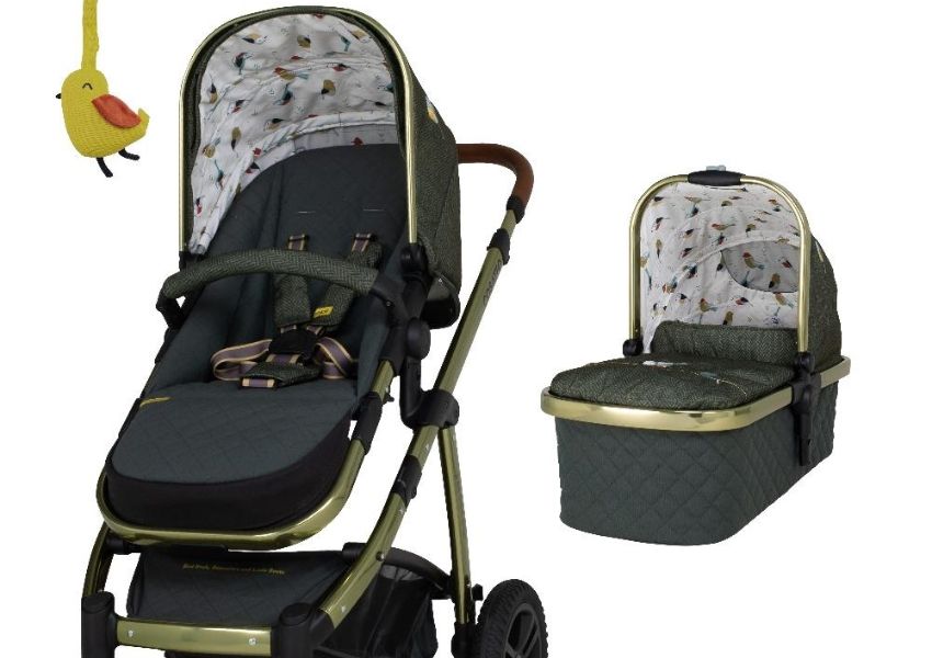 Dark green baby stroller and bassinet with gold frames, bird-patterned interiors, and a yellow bird toy.