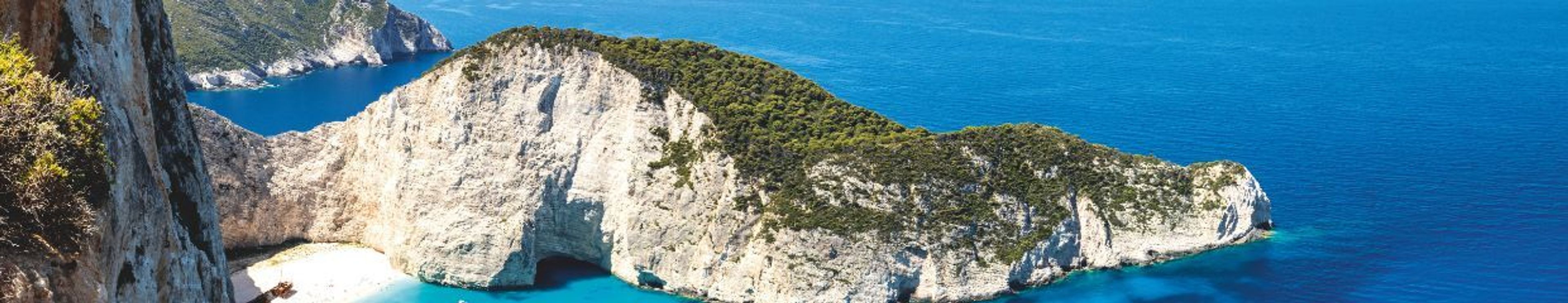 Panoramic view of a stunning bay with towering white cliffs, a small white sand beach, and vibrant turquoise water.