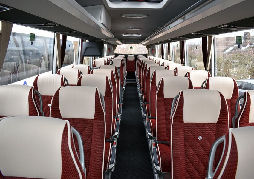 Interior view of an empty coach with rows of maroon and cream quilted seats