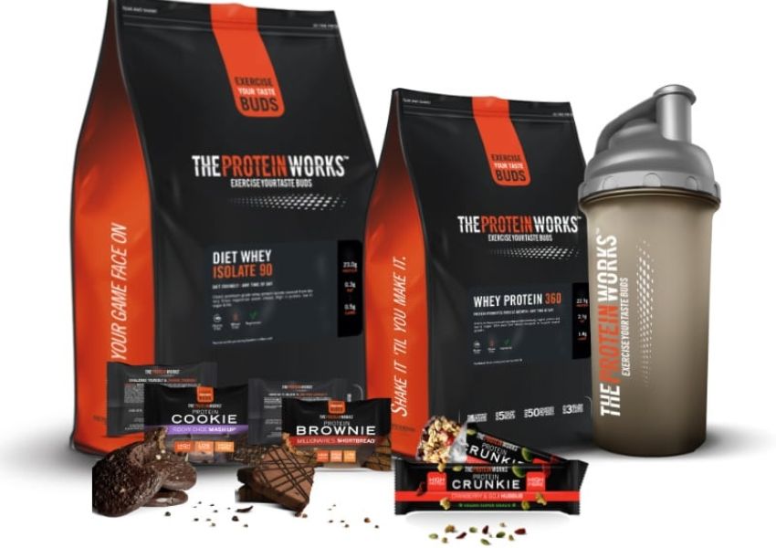 THE PROTEIN WORKS protein powder bags, shaker bottle, and various protein snacks including cookies, brownies, and a Crunkie bar.