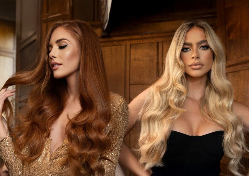 Two women with long, wavy hair; one with auburn hair in a gold top, the other with blonde hair in a black top.