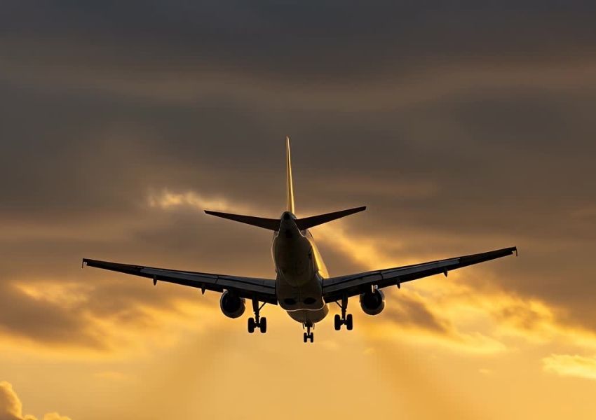 Airplane silhouetted against a golden sunset sky.