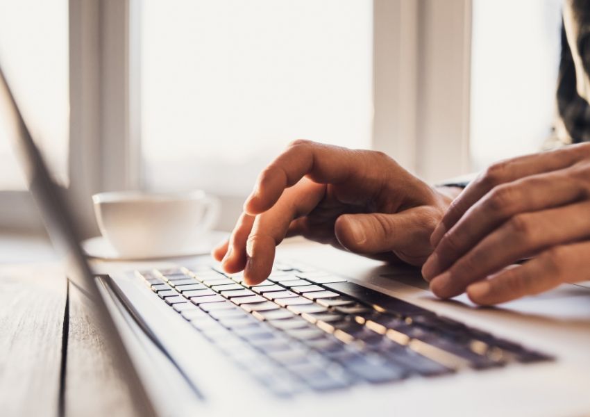 Hands typing on a laptop keyboard.