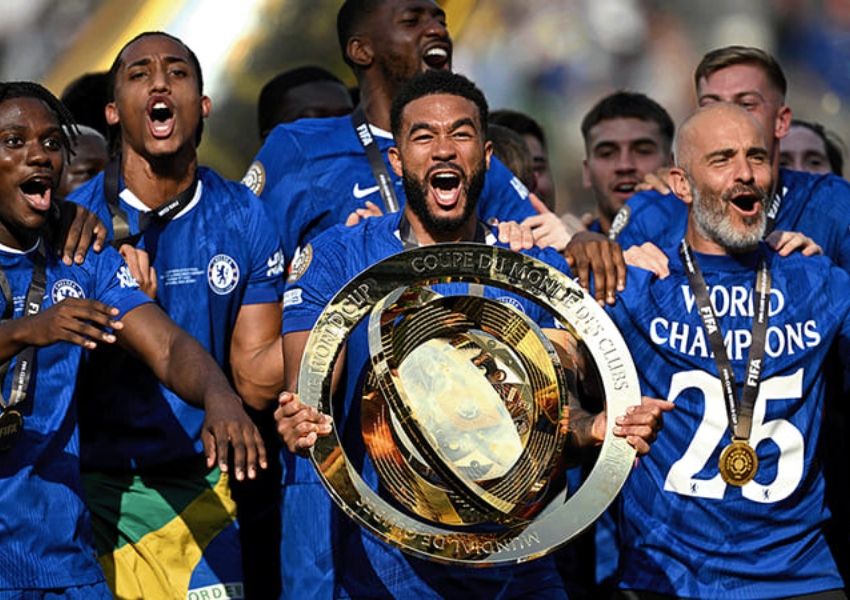 Jubilant football players and a coach in blue shirts celebrate with the FIFA Club World Cup trophy.