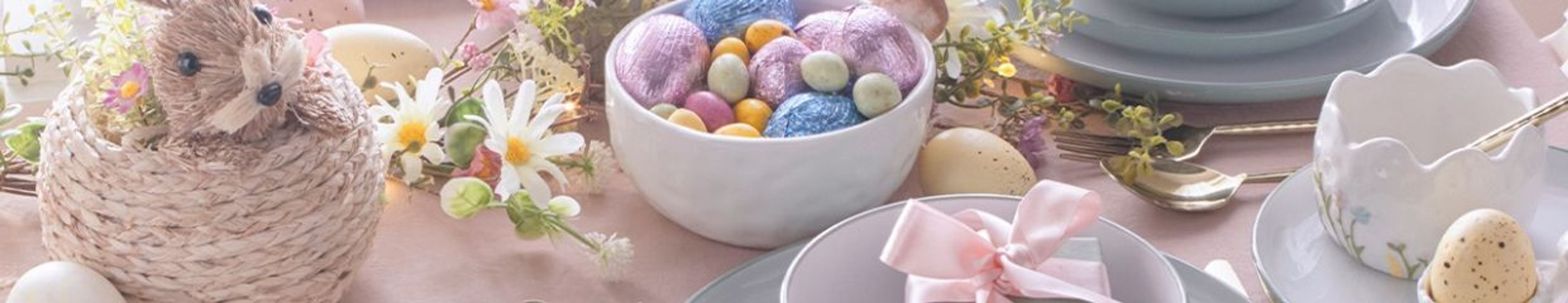 A festive Easter table setting with a bunny, colorful eggs, and candies.