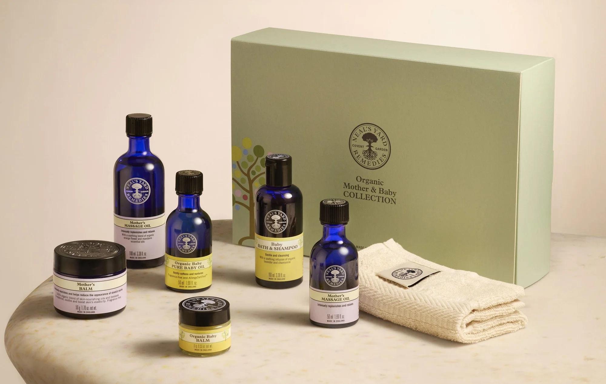 Neal's Yard Remedies Organic Mother & Baby Collection gift set with several blue bottles, jars, and a folded towel.