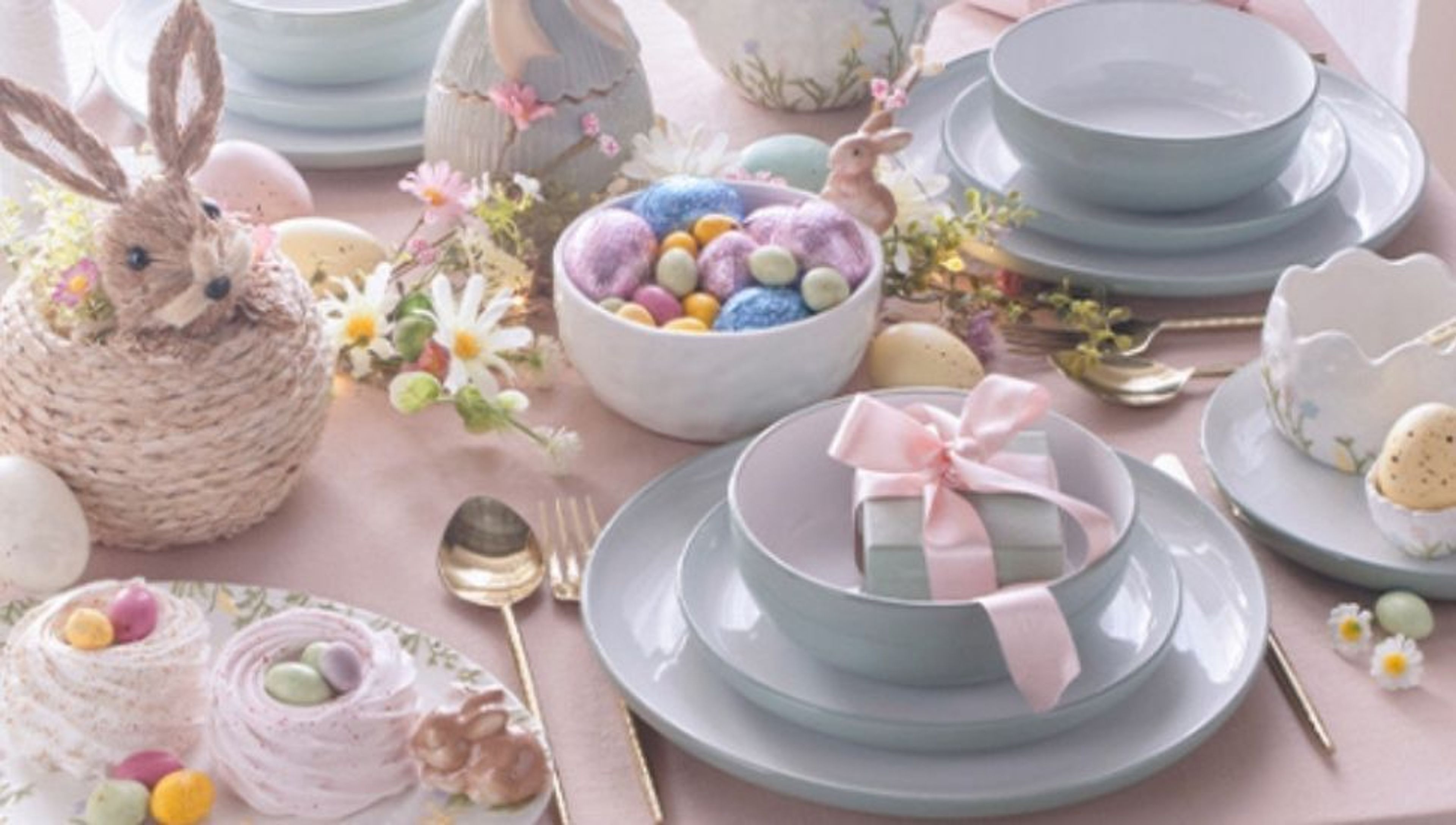 A pastel-themed Easter table setting with bunny decor, colorful eggs, and sweet treats.