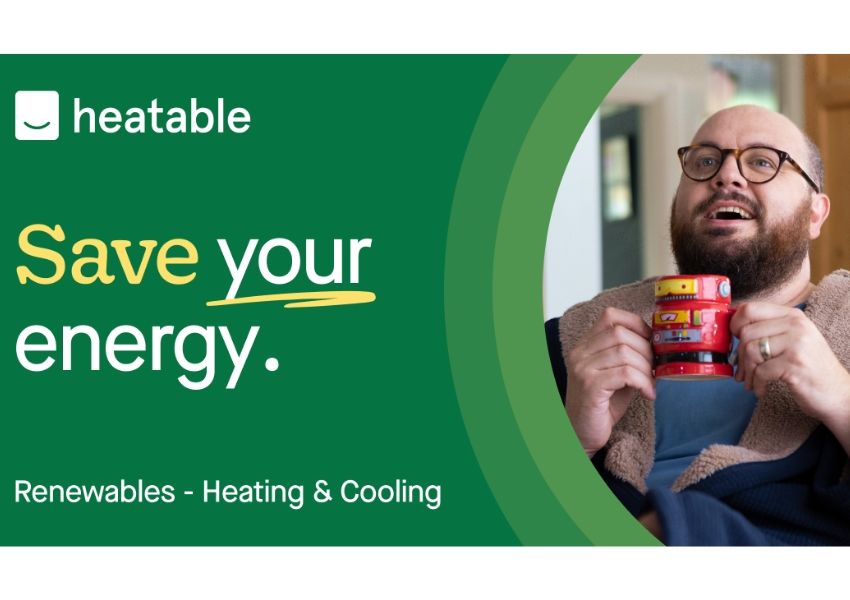 Ad for heatable featuring a smiling man in glasses holding a red robot mug, with text "Save your energy. Renewables - Heating & Cooling."