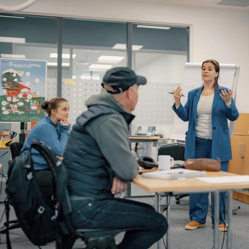 Norskopplæring i klasserom. En underviser står foran en gruppe elever som hører etter.