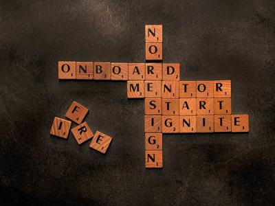 scrabble board containing the words onboard, mentor, start, ignite and no resign