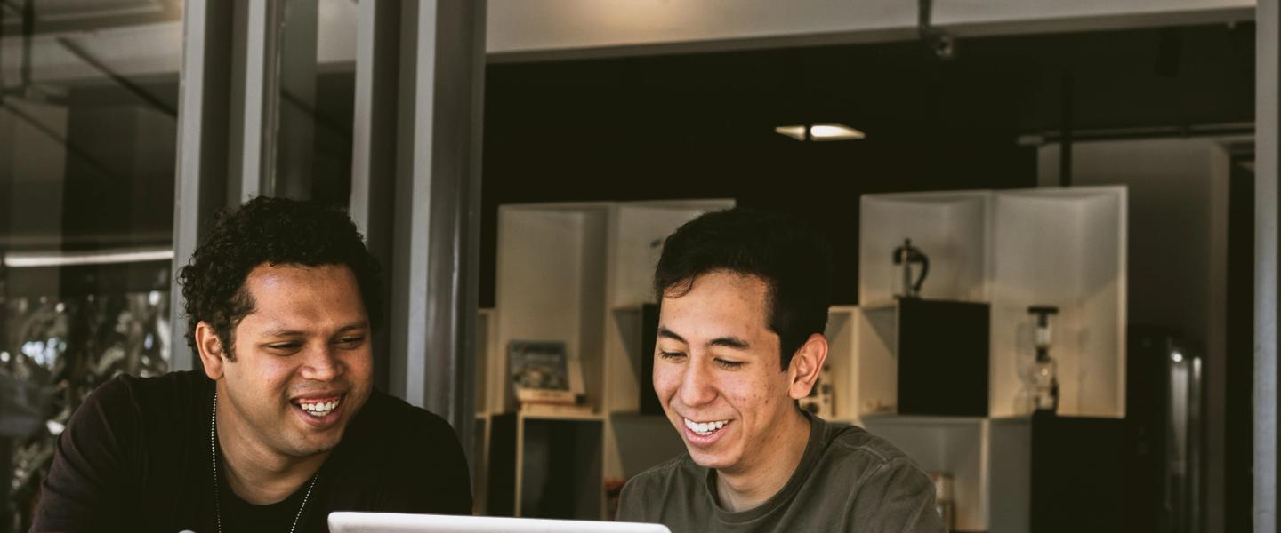 two male looking at a laptop smiling