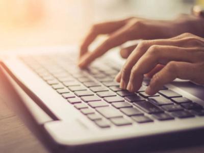 White man's hand typing on his laptop