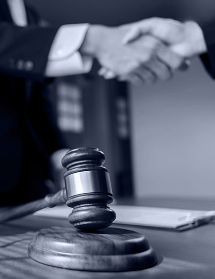 Gavel on table in front of handshake. Legal or deal-making concept.