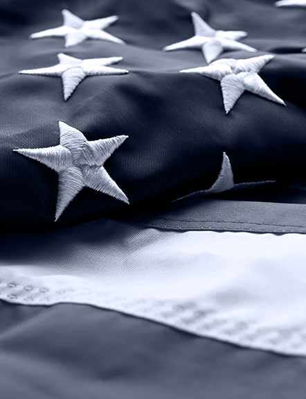 Close-up of American flag with white stars on blue fabric, and part of a white stripe.