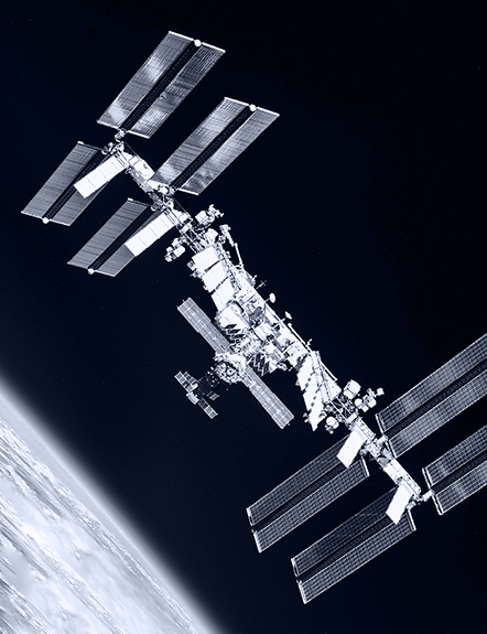 The International Space Station (ISS) in orbit, with Earth's horizon visible. The ISS has large solar panels.