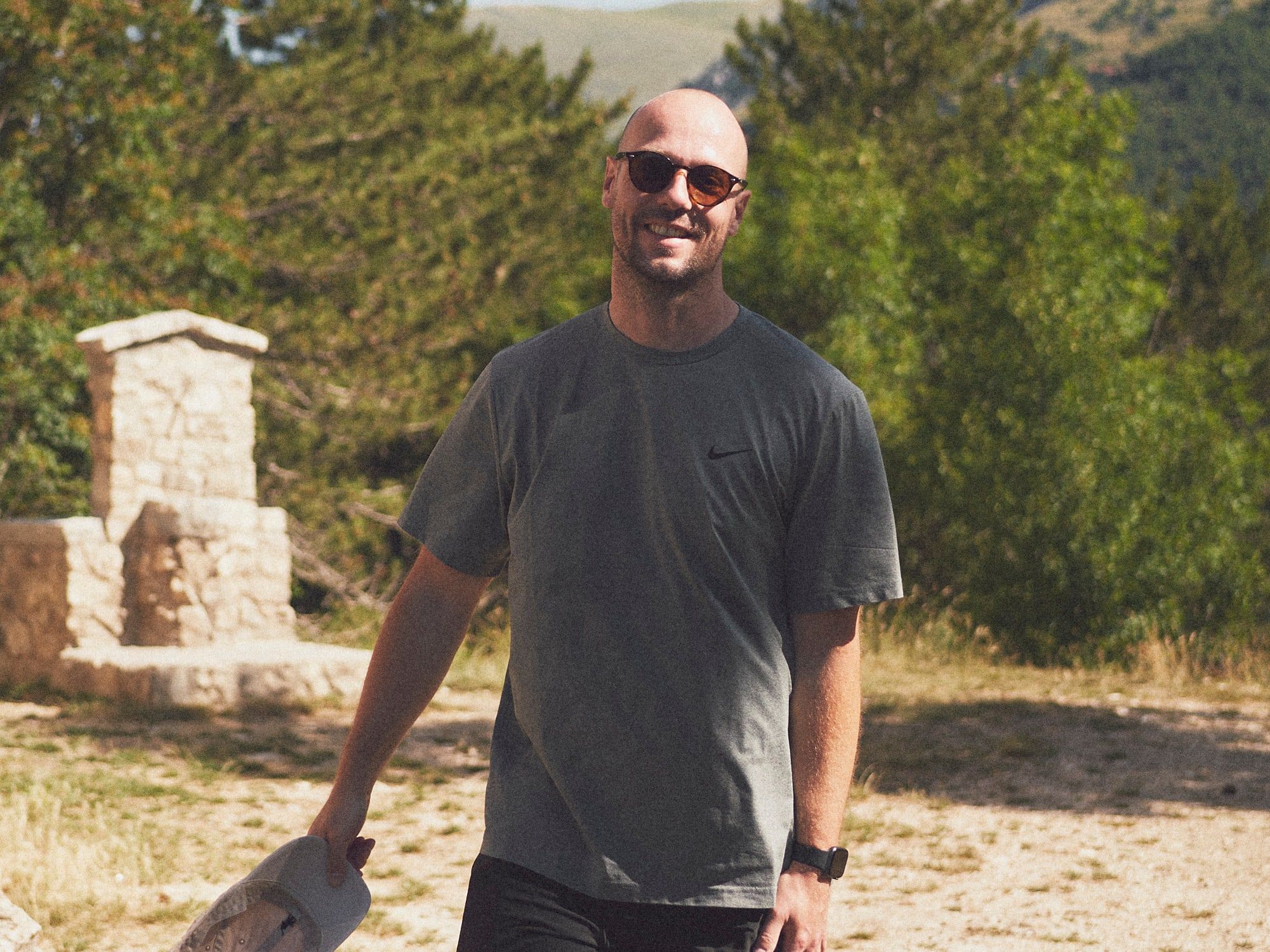 Bob van Aubel smiling on a gravel path in the mountains, cap in hand.