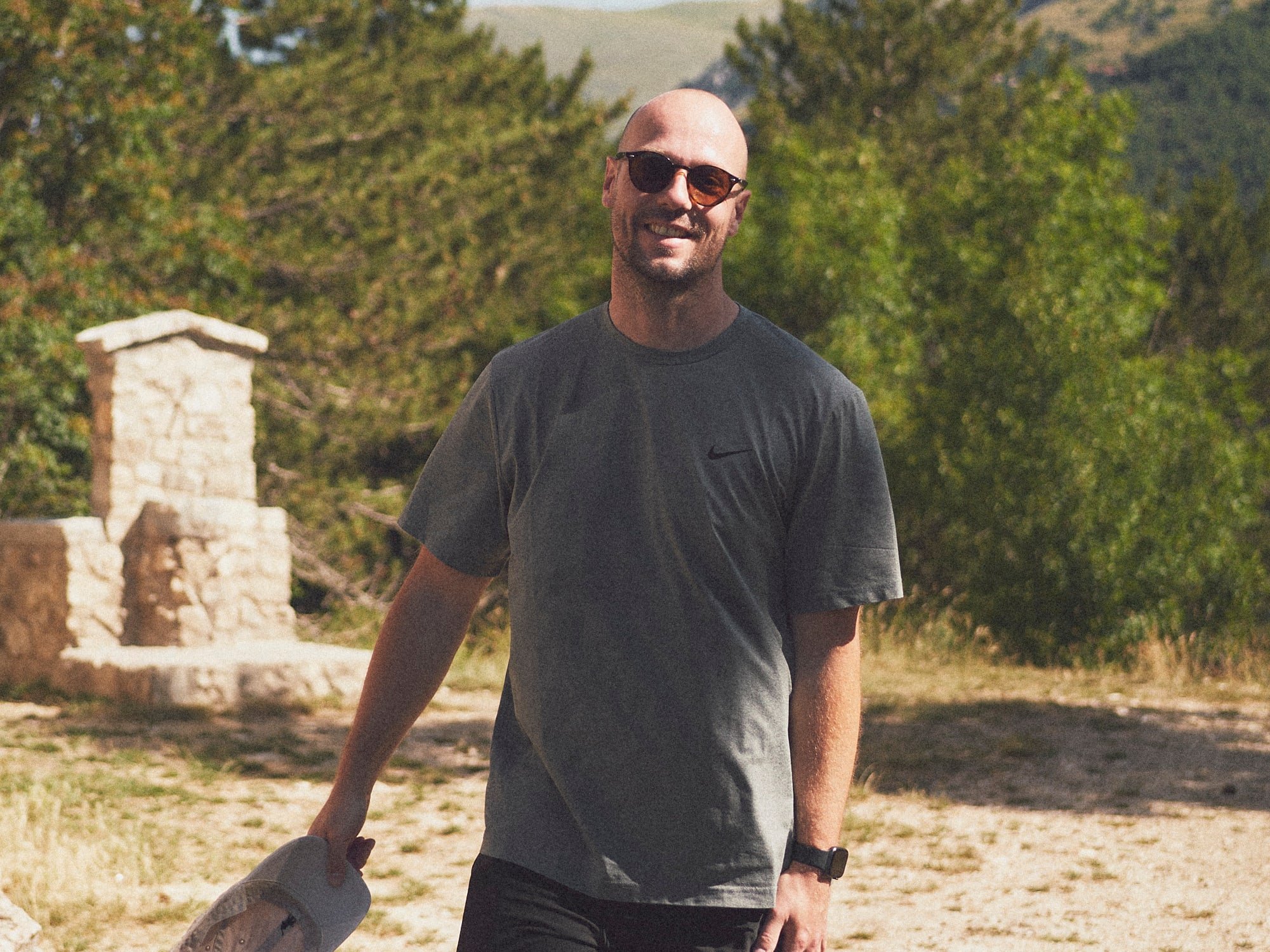 Bob van Aubel smiling on a gravel path in the mountains, cap in hand.