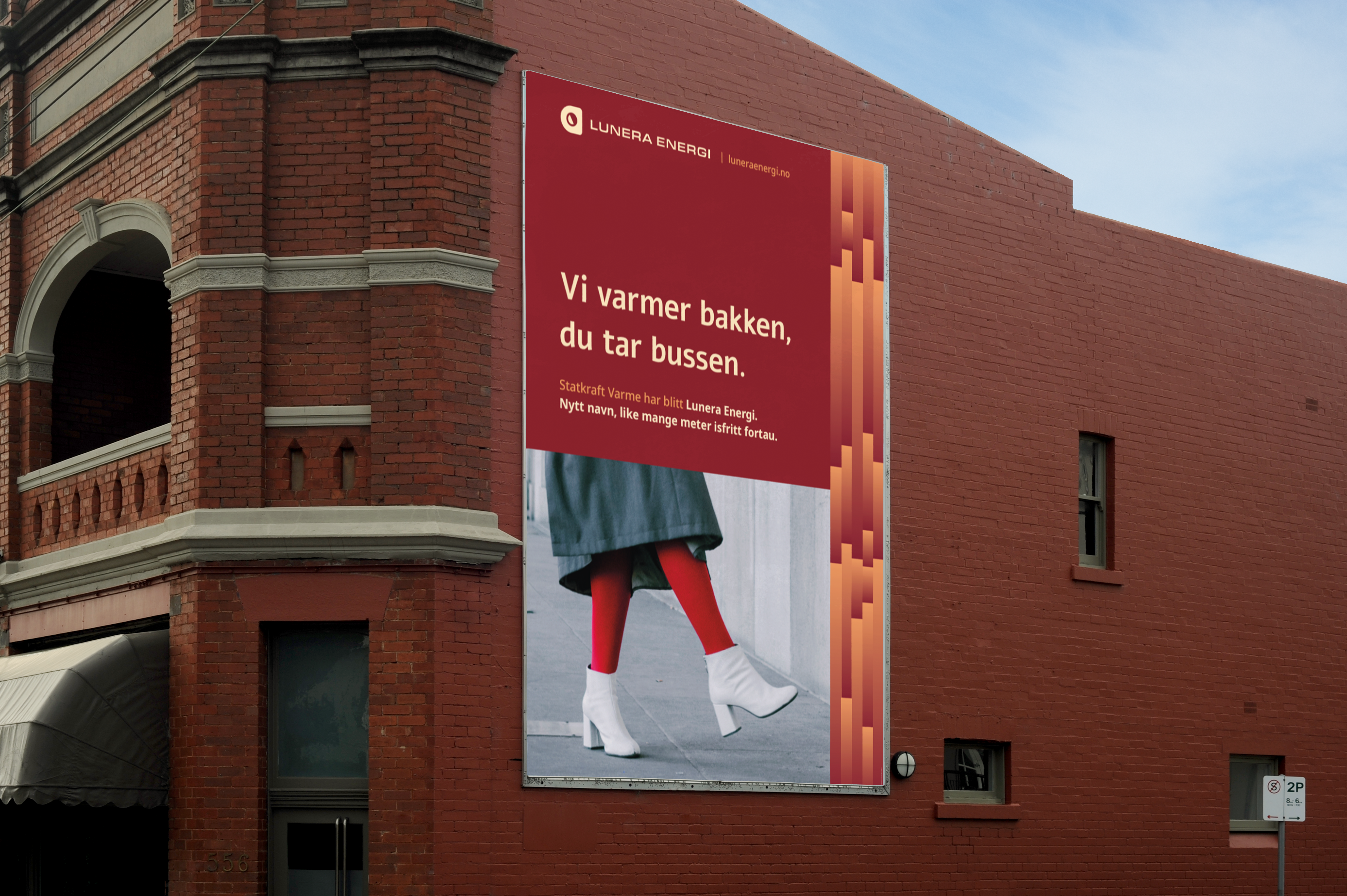 Plakat på en rød murvegg: «Vi varmer bakken, du tar bussen». Under teksten går et par i røde strømpebukser og hvite støvletter på et bart fortau.