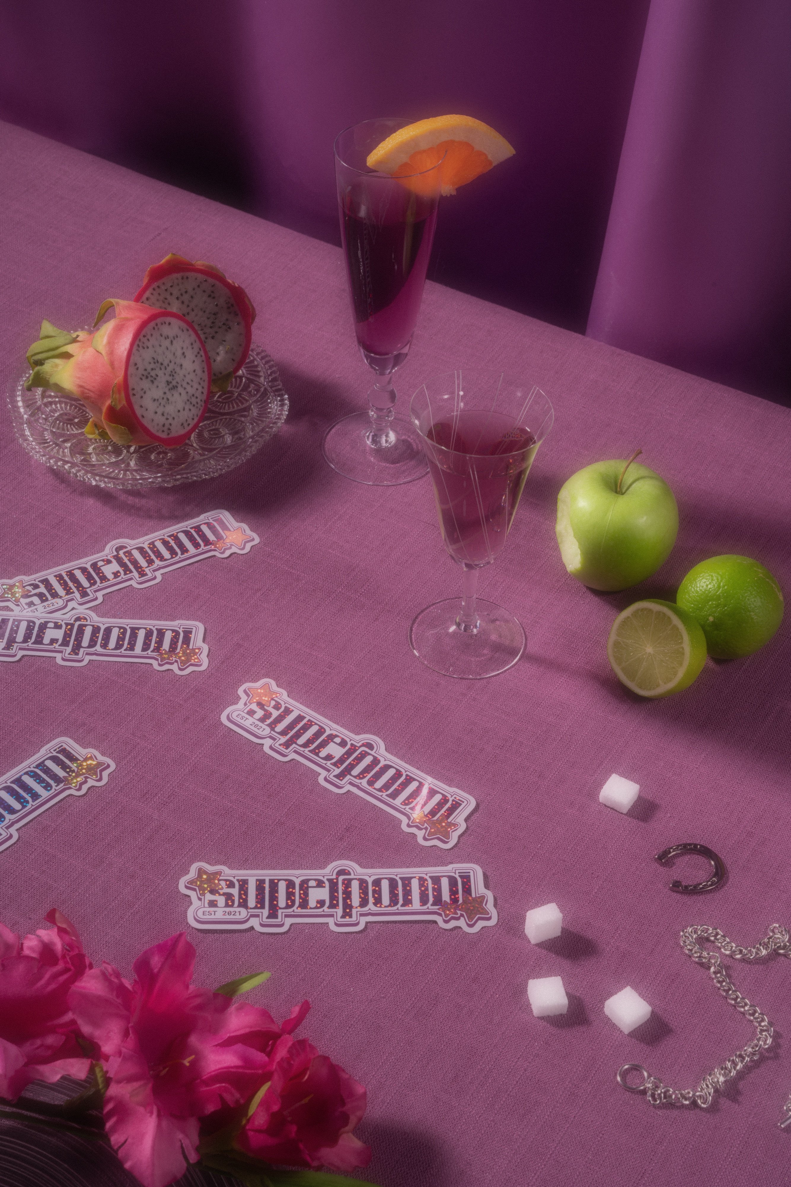 Superponni-klistremerker, epler, lime og drinker på en lilla duk