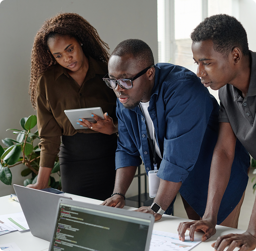 Three tech workers looking at a laptop.