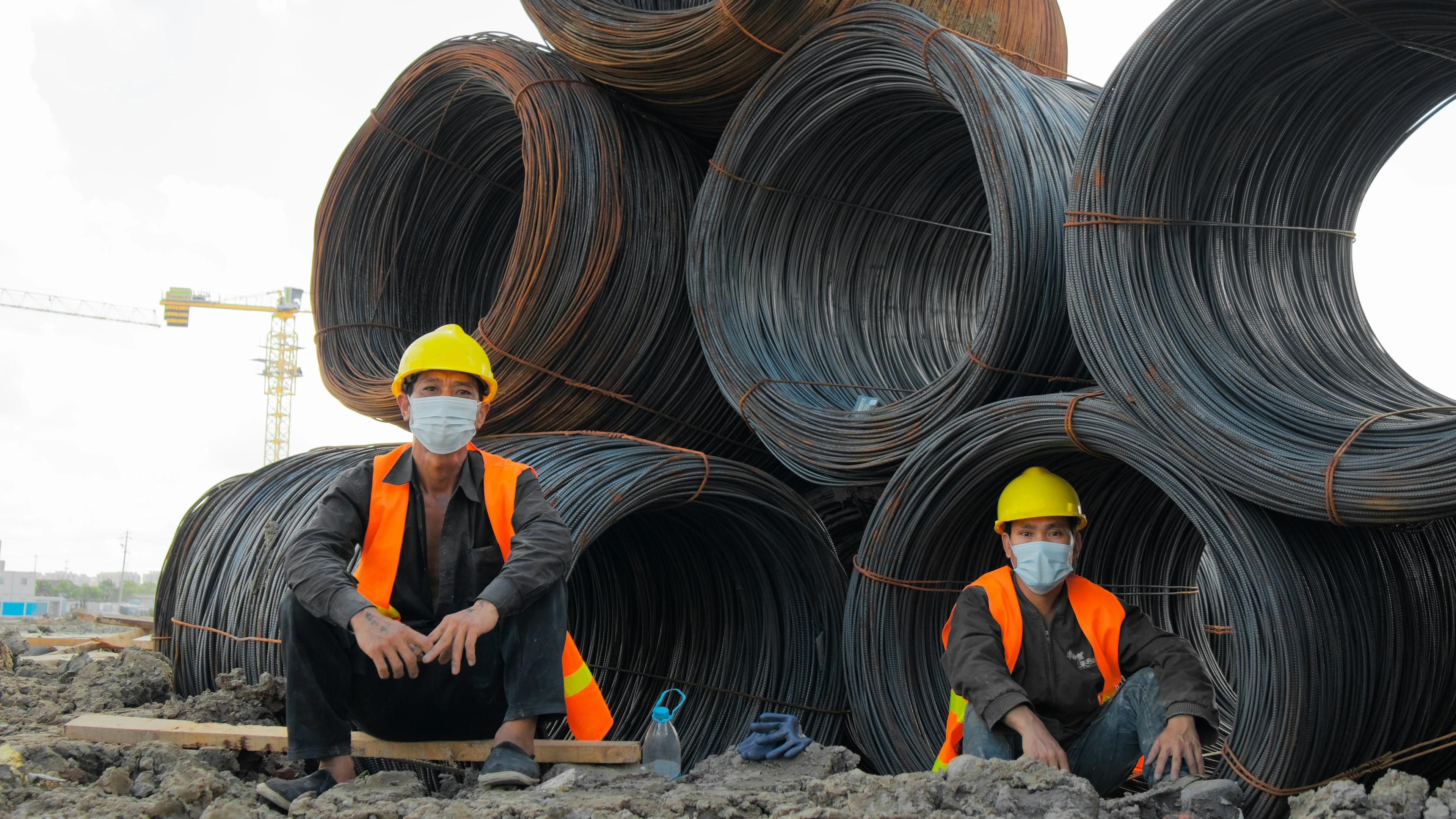 Workers sitting near coils of steel