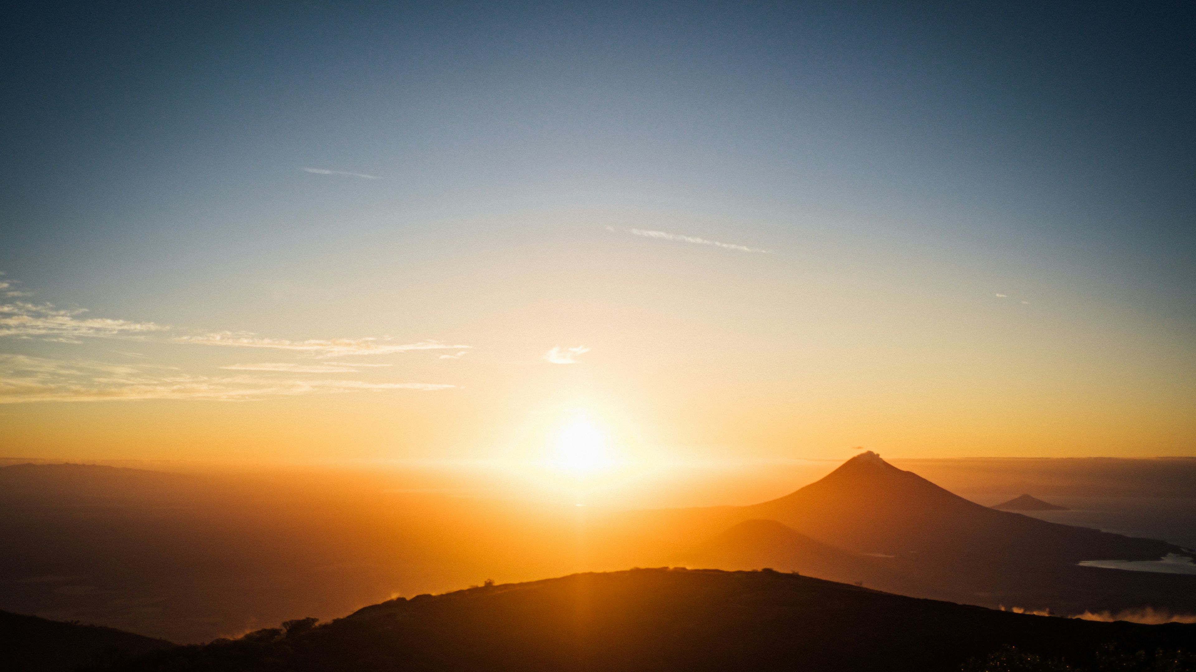 the sun is rising over a mountain range in the distance.
