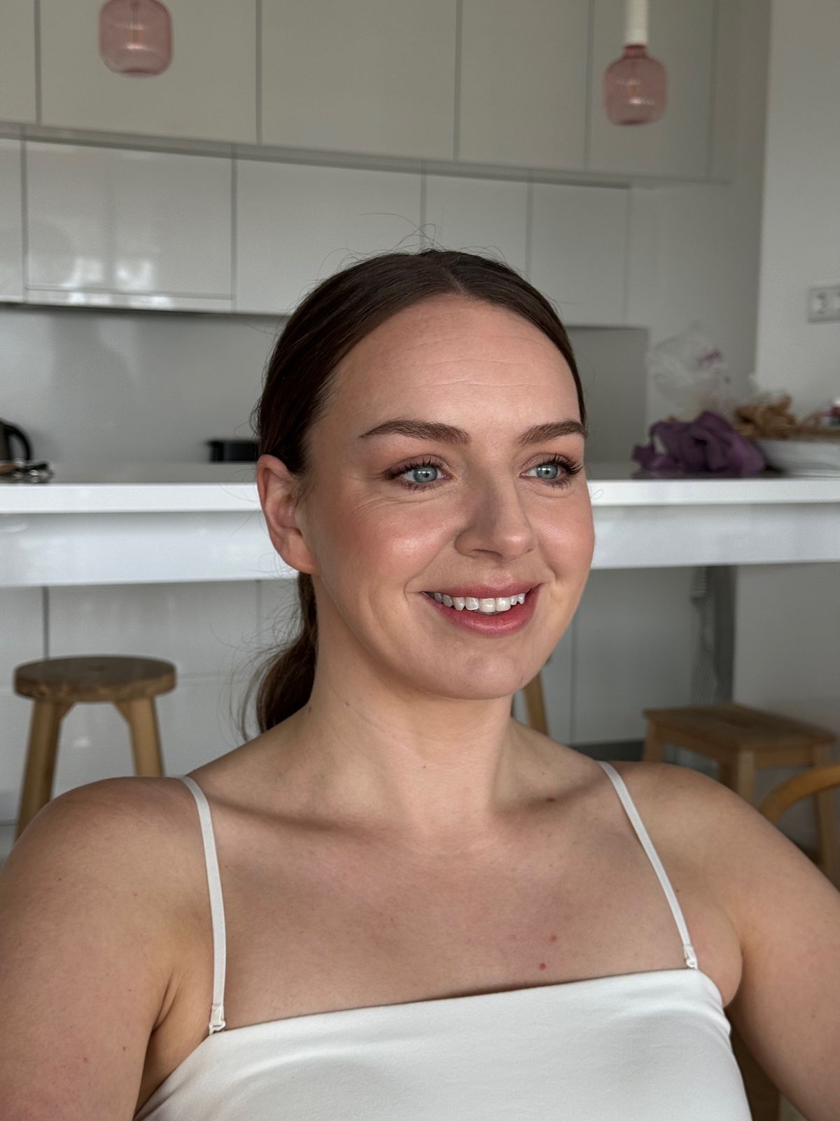 Bride with her hair tied back and softly defined eyes, photographed after her makeup is finished