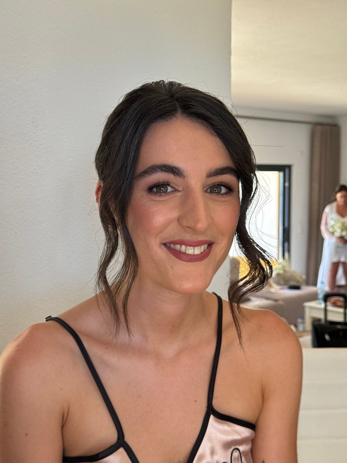 Bride with loose face-framing curls and a deep berry lip, photographed before she dresses