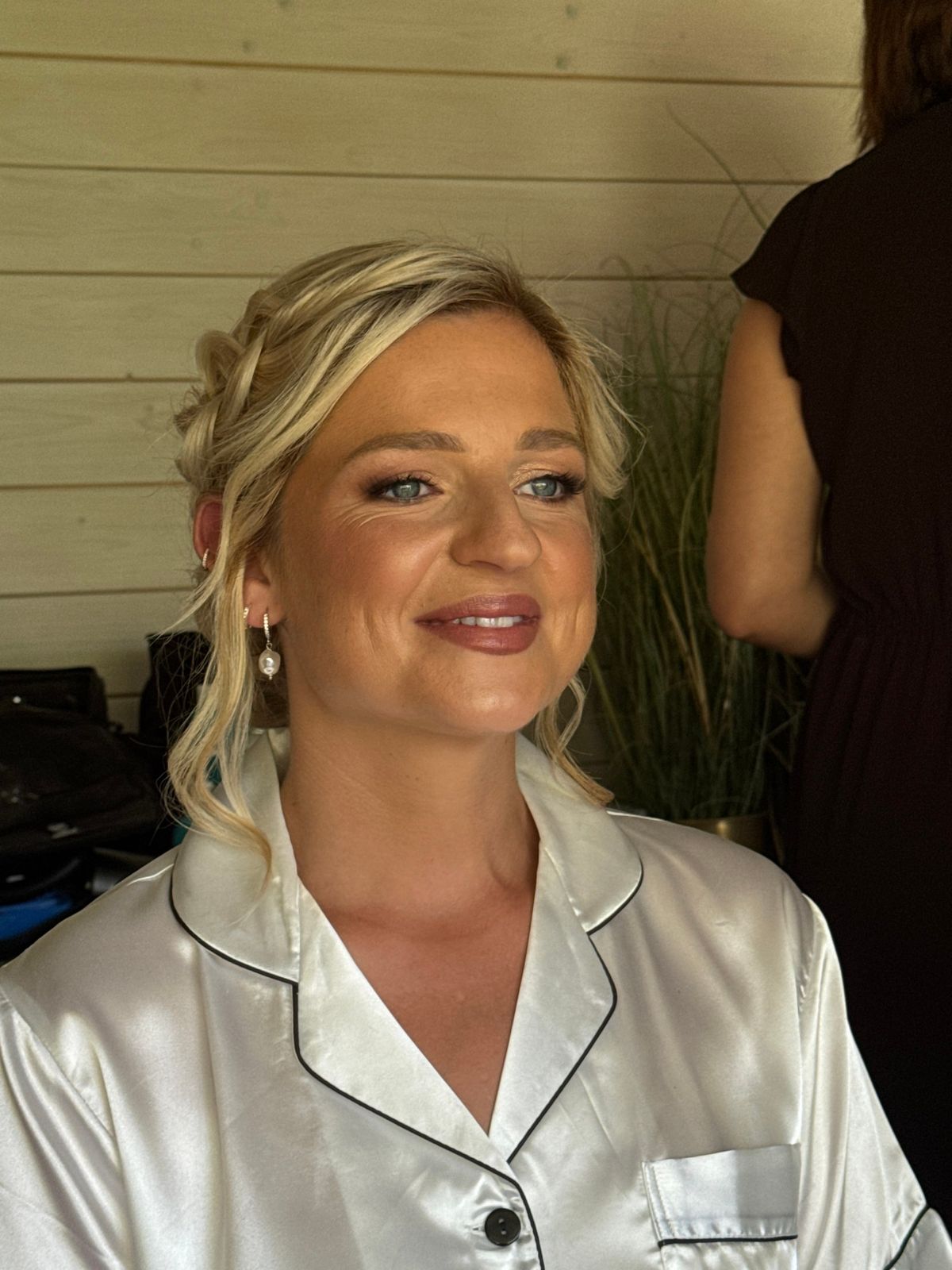 Bride with a braided updo and warm, luminous makeup, photographed in her satin pyjamas before the ceremony