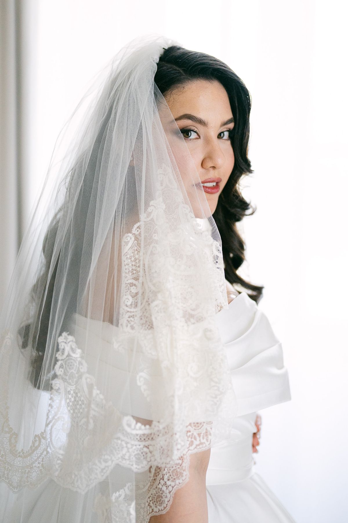 Bride with dark hair and a cathedral veil, wearing soft rose-toned bridal makeup