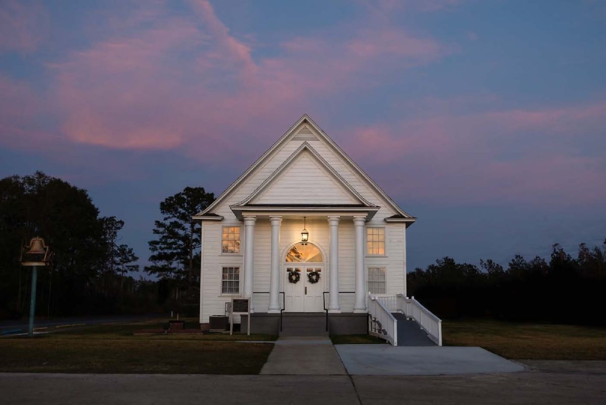 First Baptist Longville chapel at dusk, its white portico lit from within