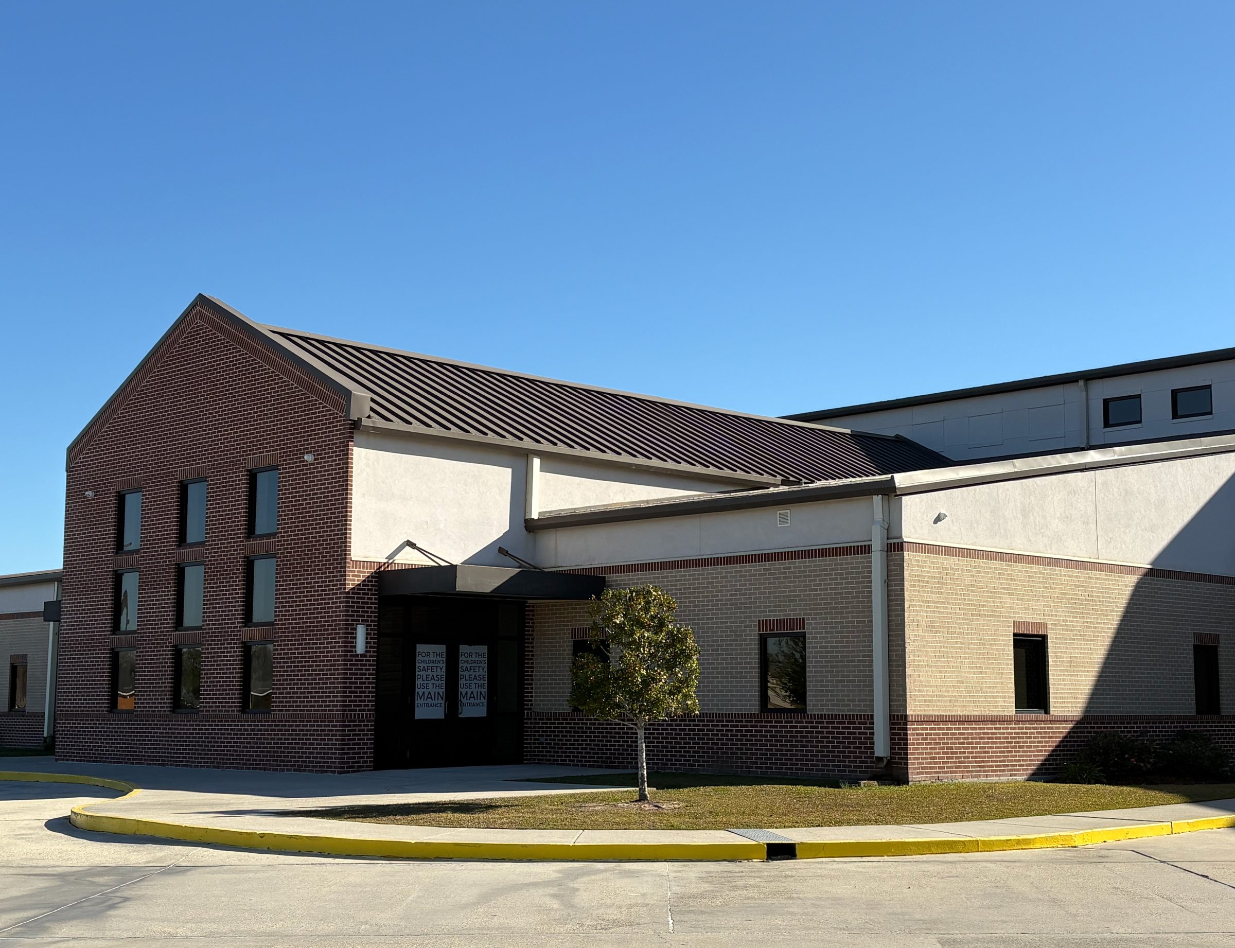 Brick church and school building beneath a standing-seam metal roof